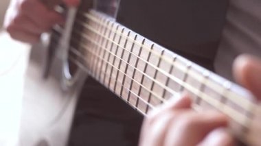 Akustik gitar dizeleri çalarken titreşir. Gitar fretboard ve erkek el yakın