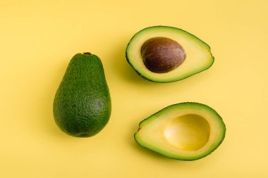Avokado düz sarı arka plan üzerinde yatıyordu. Basit ve minimal kavram. Organik sağlıklı yiyecekler. Üstte görüntü