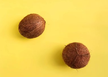 Minimalist düz sarı arka plan üzerinde hindistan cevizi ile yatıyordu. Üst Görünüm. Pop art tasarım, yaratıcı yaz deseni.