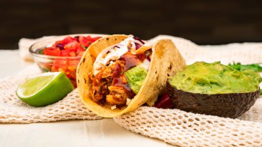 Meksika geleneksel ev yapımı domuz etli, acılı, acılı, domates salatası, avokado soslu ve soslu tako.