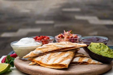 Meksika geleneksel ev yapımı domuz etli, acılı, acılı, domates salatası avokado soslu ve soslu quesadilla.