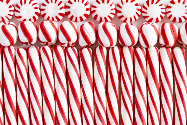 关闭一排排红色和白色条纹薄荷棒 圆形薄荷糖和旋转糖果球的背景 — 图库照片