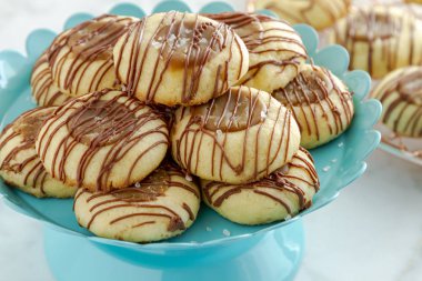 Tanımlama bilgilerini sütlü çikolata parlak mavi pasta stand ve raf arka planda soğutma bakır oturan ile drizzled tuzlu karamel parmak izi, yakın çekim