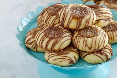 Tanımlama bilgilerini sütlü çikolata kopya alanı sol ile parlak mavi pasta sandalyesinde oturan ile drizzled tuzlu karamel parmak izi, yakın çekim