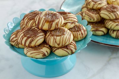 Tuzlu karamel parmak izi tanımlama bilgilerini sütlü çikolata parlak mavi pasta ve arka planda ek tanımlama bilgilerini mavi plaka üzerinde oturan ile drizzled