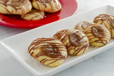 Tuzlu karamel parmak izi tanımlama bilgileri satır arka planda kırmızı plaka üzerinde ek tanımlama ile beyaz tabakta sütlü çikolata ile drizzled
