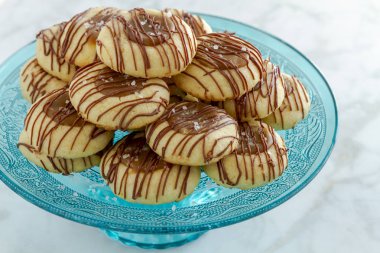 Tuzlu karamel parmak izi tanımlama bilgilerini sütlü çikolata mermer masa üstü dekoratif mavi cam Mantı sandalyesinde oturan ile drizzled