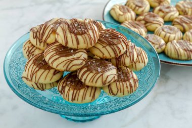 Tuzlu karamel parmak izi tanımlama bilgilerini sütlü çikolata dekoratif mavi cam Mantı stand ve arka planda mavi plaka üzerinde ek tanımlama bilgilerini oturan ile drizzled