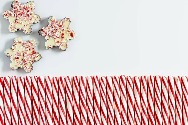 背景的三个巧克力薄荷树皮雪花与一排红色和白色条纹薄荷糖果和复制空间 — 图库照片