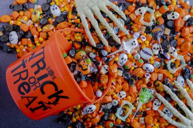 Halloween candy spilling out of orange trick or treat bucket clipart
