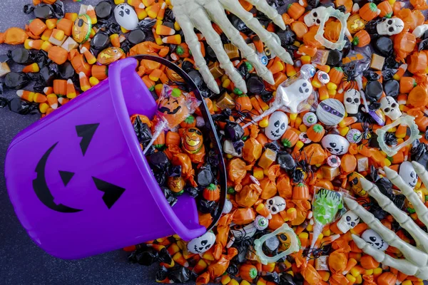 Halloween candy spilling out of purple pumpkin bucket — Stock Photo, Image