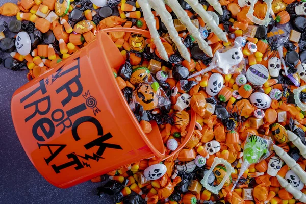 Halloween candy spilling out of orange trick or treat bucket