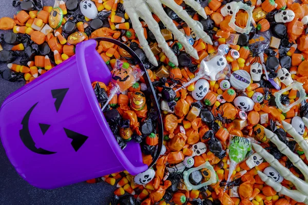 Halloween candy spilling out of purple pumpkin bucket — Stock Photo, Image