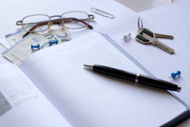 Masanın üzerinde kalem ve gözlük olan defter. 