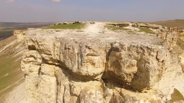 Afdaling van een bergplateau over witte gebarsten rotsen. Birds eye view. — Stockvideo