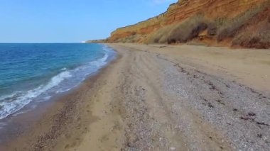 Kahverengi taş yanındaki sahil hattı boyunca devam