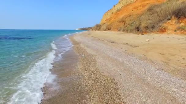 Volver a lo largo de la línea de playa junto a las rocas marrones — Vídeos de Stock