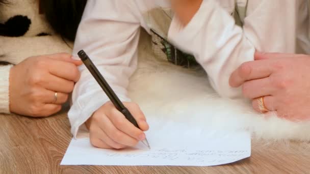 Barnens händer skriva på ett papper. — Stockvideo