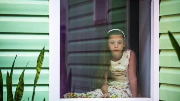 La chica está sentada fuera de la ventana y esperando el final de la lluvia — Vídeos de Stock