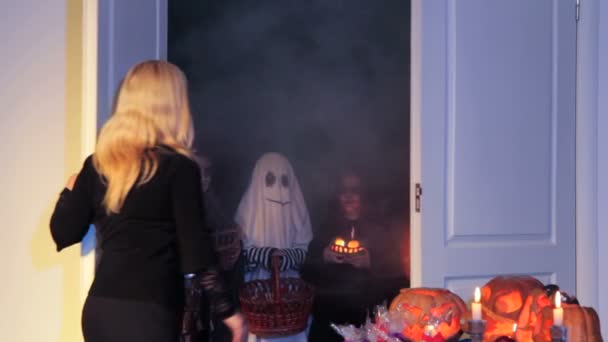 En kvinna ger ut godis till barn för halloween — Stockvideo