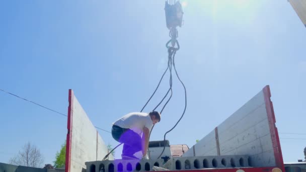 Los hombres pegan una losa de hormigón al gancho de una grúa de camión — Vídeos de Stock
