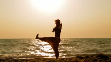Kız plajda yoga egzersizi yapıyor.