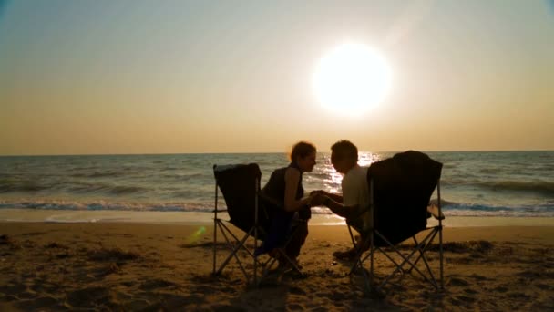 Casal sentado em poltronas de frente para o mar — Vídeo de Stock