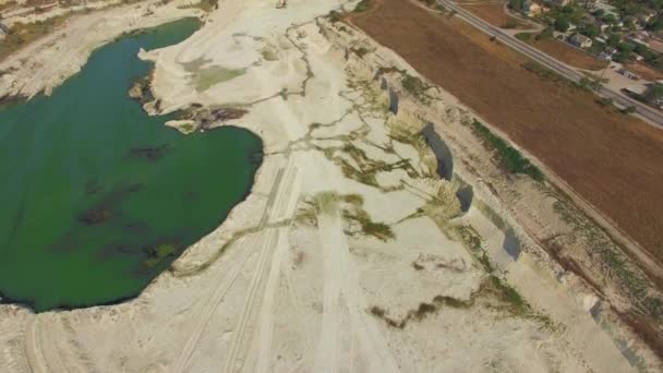 Eine Drohne fliegt über einen Steinbruch, einen See und ein Feld — Stockvideo