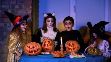 Cadılar Bayramı kostümlü çocuklar bir mum söndürür.