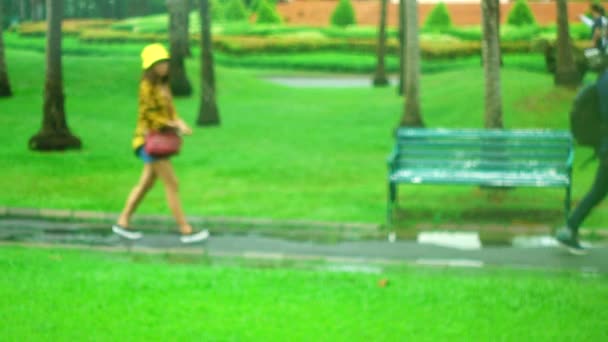 Parc de flou 4K les gens marchent et font de l'exercice pendant qu'il pleut des parapluies 