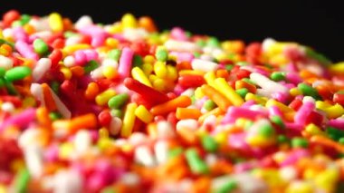 4K Lezzetli tatlı donut tabakta dönüyor. Üst Manzara. Parlak ve renkli donut serpiştirilmiş yakın çekim makro çekim siyah arka planda dönüyor.