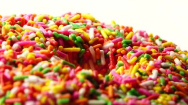 4K Lezzetli tatlı donut tabakta dönüyor. Üst Manzara. Parlak ve renkli donut serpiştirilmiş yakın çekim makro çekim beyaz arka planda dönüyor.