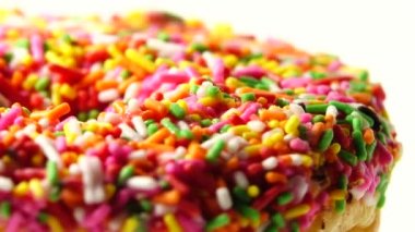 4K Lezzetli tatlı donut tabakta dönüyor. Üst Manzara. Parlak ve renkli donut serpiştirilmiş yakın çekim makro çekim beyaz arka planda dönüyor.