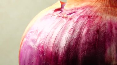 Dilimlenmiş kırmızı soğan halkaları 4K 'da dönüyor. Zengin vitaminli sebzeli sağlıklı gıda arka planının yakın görüntüsü