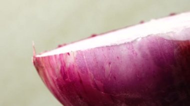 Dilimlenmiş kırmızı soğan halkaları 4K 'da dönüyor. Zengin vitaminli sebzeli sağlıklı gıda arka planının yakın görüntüsü