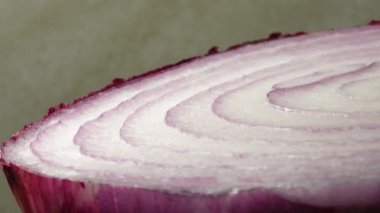 Dilimlenmiş kırmızı soğan halkaları 4K 'da dönüyor. Zengin vitaminli sebzeli sağlıklı gıda arka planının yakın görüntüsü