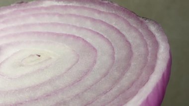 Dilimlenmiş kırmızı soğan halkaları 4K 'da dönüyor. Zengin vitaminli sebzeli sağlıklı gıda arka planının yakın görüntüsü