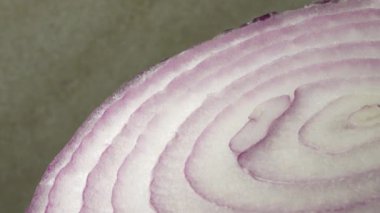 Dilimlenmiş kırmızı soğan halkaları 4K 'da dönüyor. Zengin vitaminli sebzeli sağlıklı gıda arka planının yakın görüntüsü
