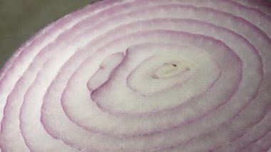 Dilimlenmiş kırmızı soğan halkaları 4K 'da dönüyor. Zengin vitaminli sebzeli sağlıklı gıda arka planının yakın görüntüsü