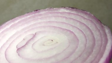 Dilimlenmiş kırmızı soğan halkaları 4K 'da dönüyor. Zengin vitaminli sebzeli sağlıklı gıda arka planının yakın görüntüsü