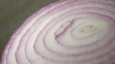 Dilimlenmiş kırmızı soğan halkaları 4K 'da dönüyor. Zengin vitaminli sebzeli sağlıklı gıda arka planının yakın görüntüsü