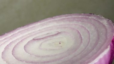 Dilimlenmiş kırmızı soğan halkaları 4K 'da dönüyor. Zengin vitaminli sebzeli sağlıklı gıda arka planının yakın görüntüsü