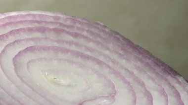 Dilimlenmiş kırmızı soğan halkaları 4K 'da dönüyor. Zengin vitaminli sebzeli sağlıklı gıda arka planının yakın görüntüsü