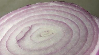Dilimlenmiş kırmızı soğan halkaları 4K 'da dönüyor. Zengin vitaminli sebzeli sağlıklı gıda arka planının yakın görüntüsü