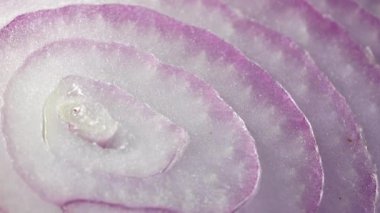 Dilimlenmiş kırmızı soğan halkaları 4K 'da dönüyor. Zengin vitaminli sebzeli sağlıklı gıda arka planının yakın görüntüsü