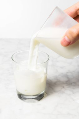 Adamın eli buzlu bardağa taze süt döküyor. Dalgona kahve hazırlığı