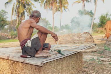 Asyalı yaşlı adam yapma bambu hasır kırsal kesimde.