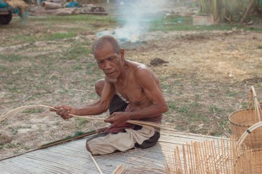 Asyalı yaşlı adam yapma bambu hasır kırsal kesimde.