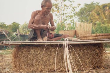 Asyalı yaşlı adam yapma bambu hasır kırsal kesimde.