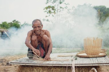 Asyalı yaşlı adam yapma bambu hasır kırsal kesimde.